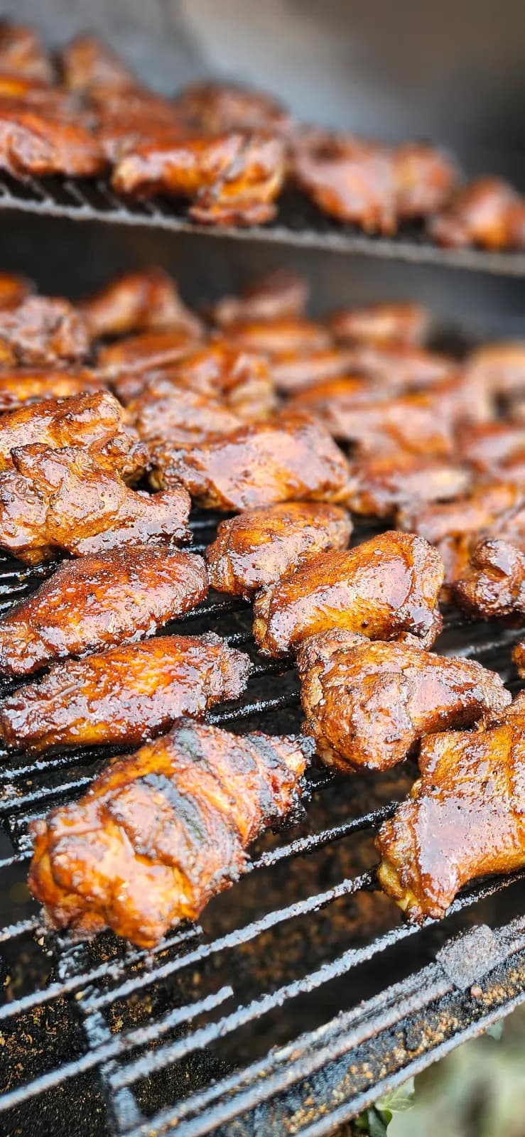 Glazed chicken wings finishing over the smoker grates.